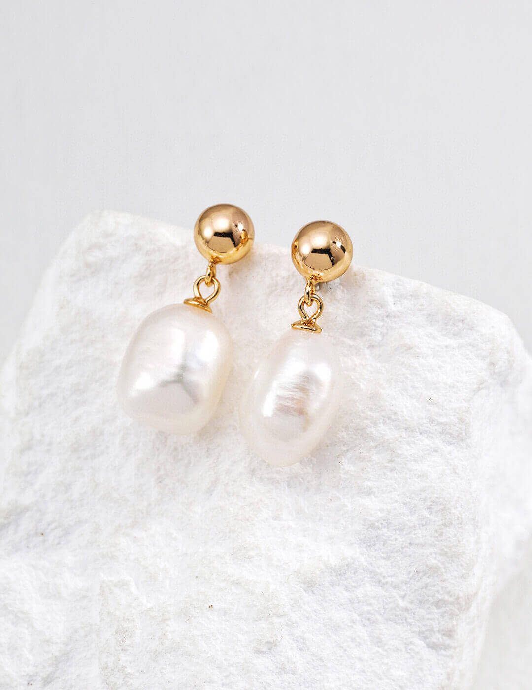 Detailed view of the 925 sterling silver setting and gold tone elements on the baroque pearl earrings.