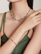 Woman wearing a green dress with a pearl necklace and bracelet against a neutral background