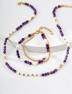 Set of purple beaded necklaces and bracelets on a white surface
