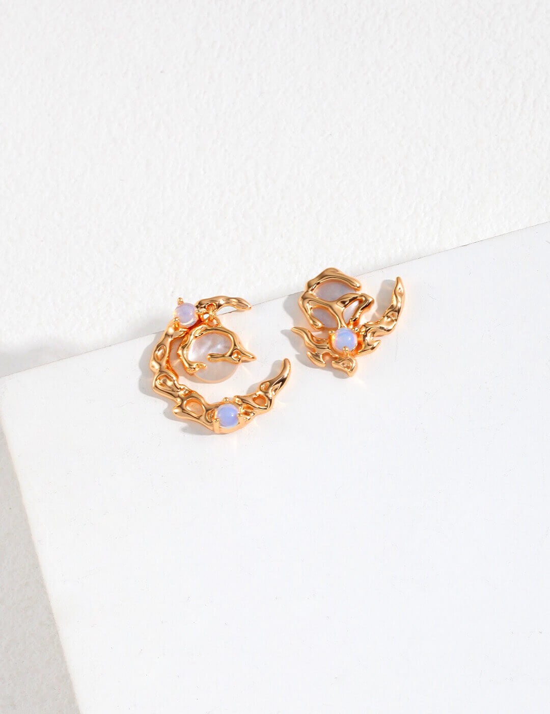 Pair of asymmetric earrings showing opal and mother of pearl design