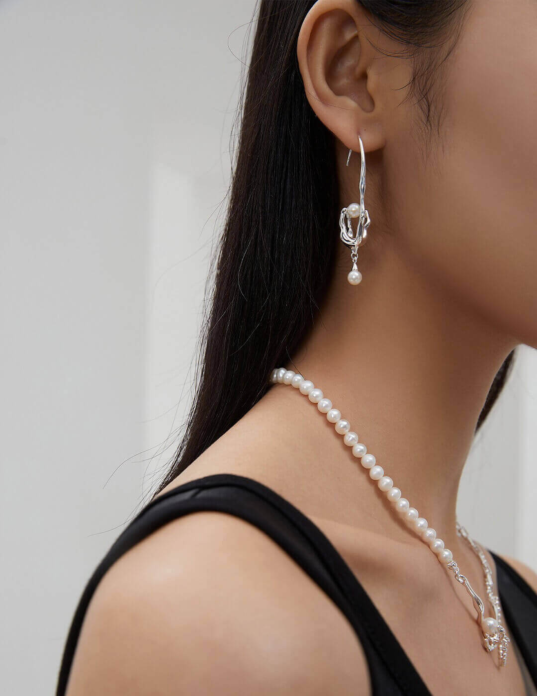 Side view of the Withered Nest asymmetric drop earrings on a model, showcasing the elegant drape and symbolic design.