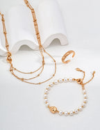Gold necklace and bracelet with pearl accents on a white background