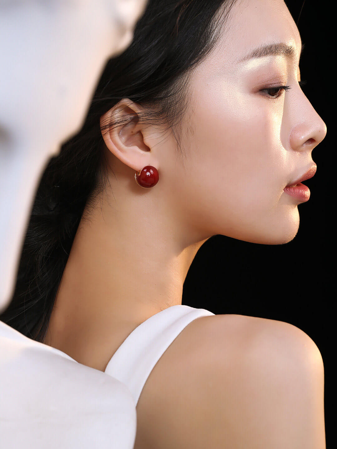 Bold red enamel earrings adding a sophisticated pop of color to professional work attire.