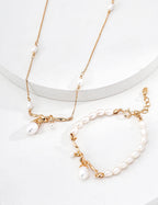Gold necklace and bracelet set with pearls on a white background
