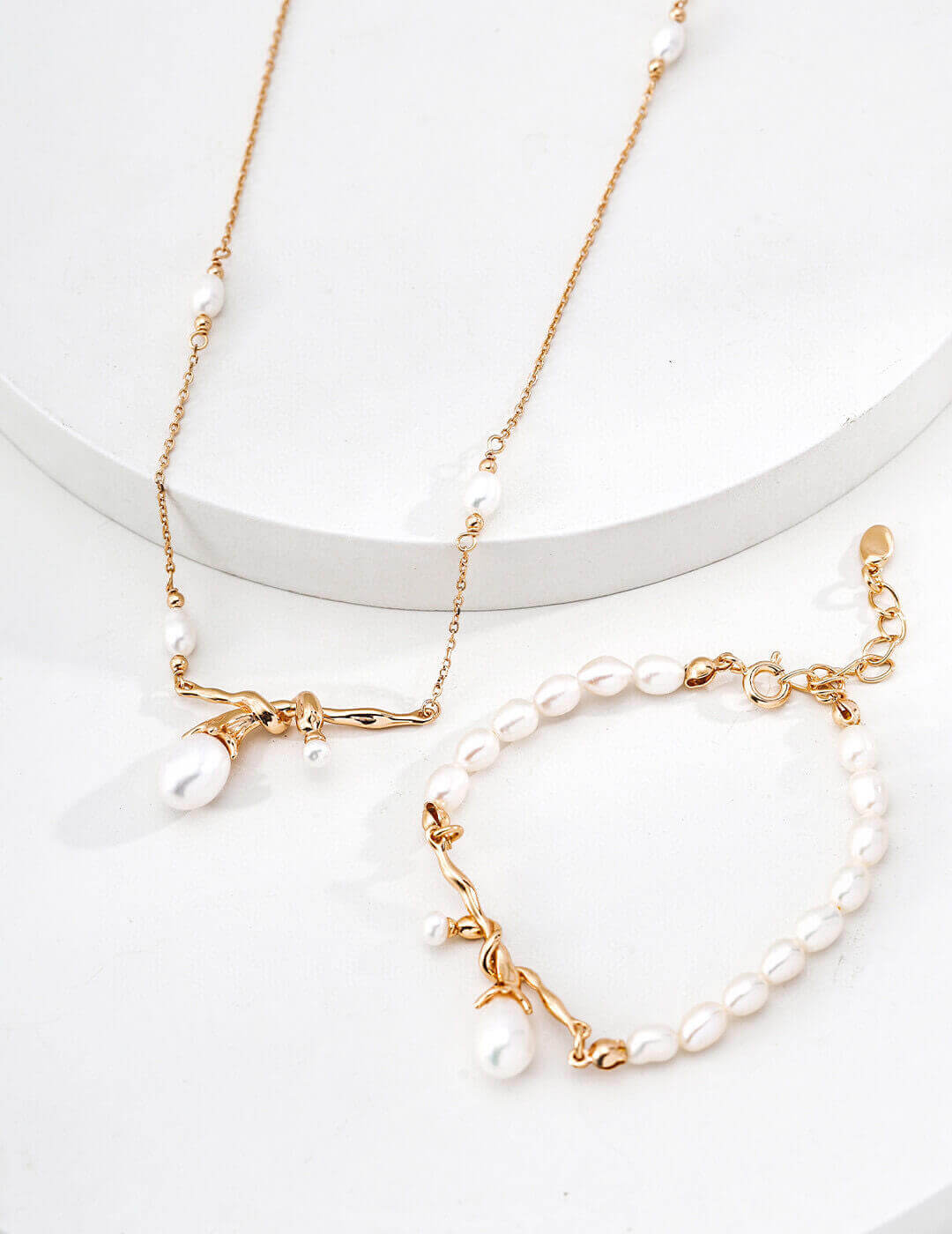 Gold necklace and bracelet set with pearls on a white background