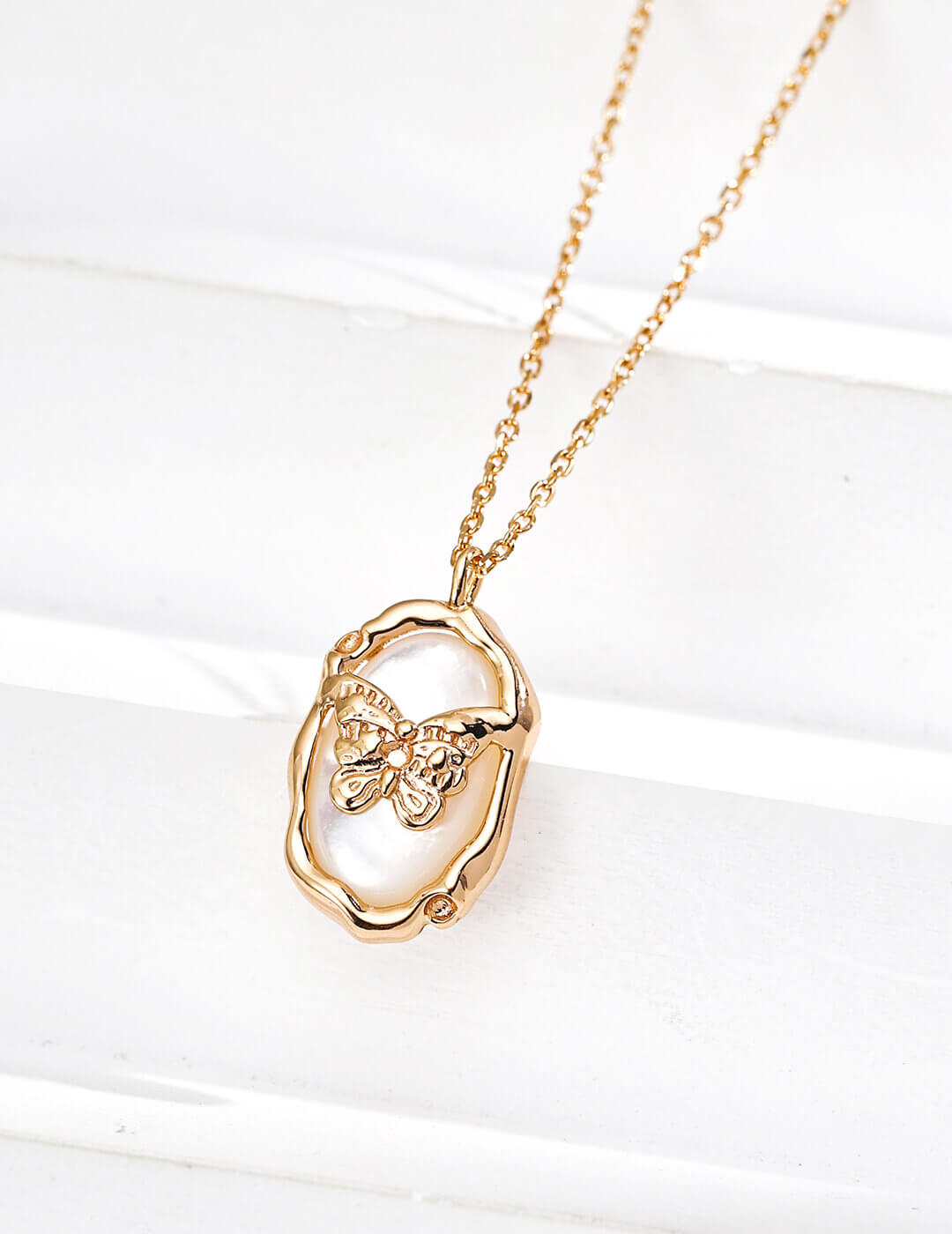 Gold necklace with a heart-shaped pendant on a white background