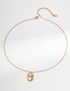 Gold necklace with a pendant on a light gray background