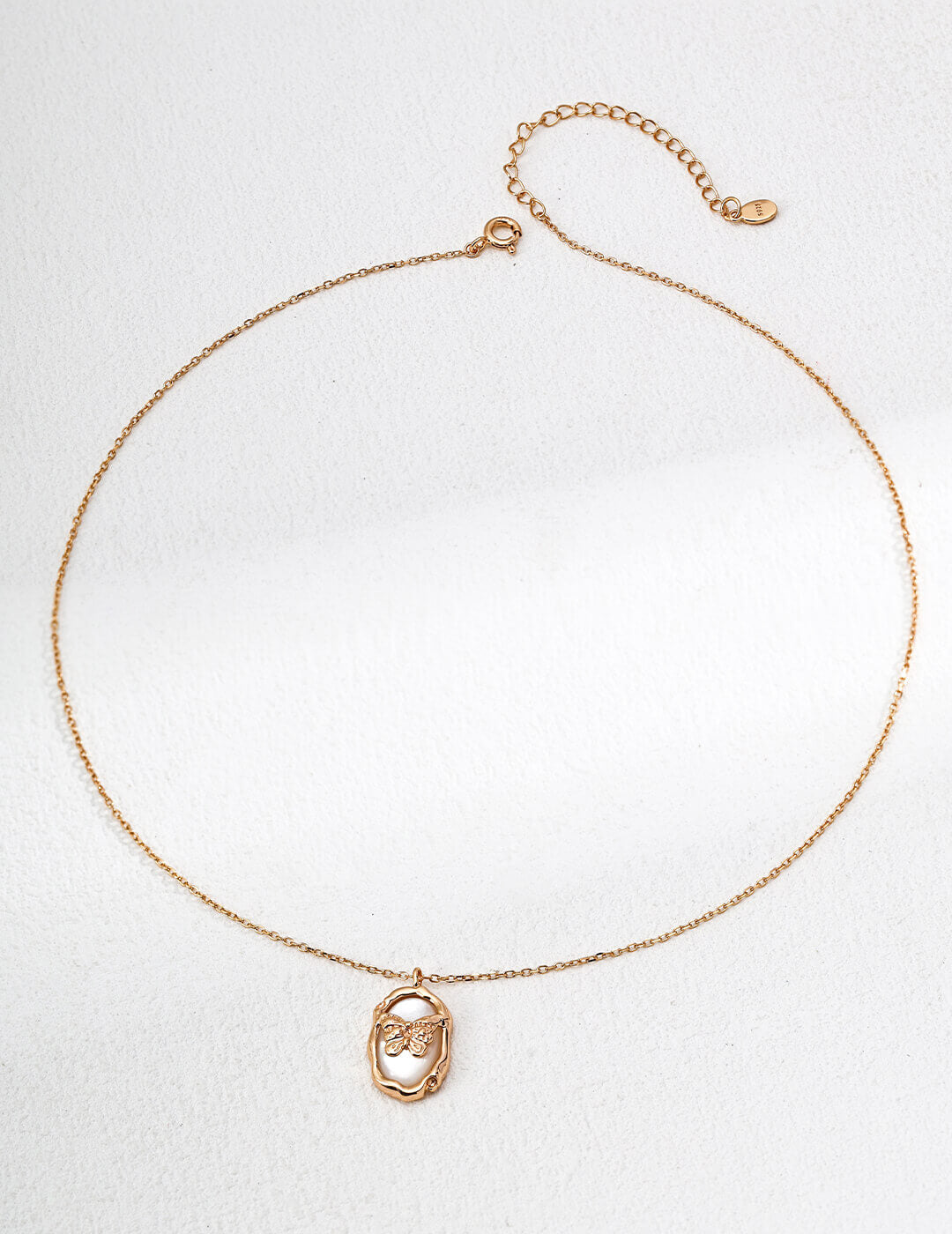 Gold necklace with a pendant on a light gray background