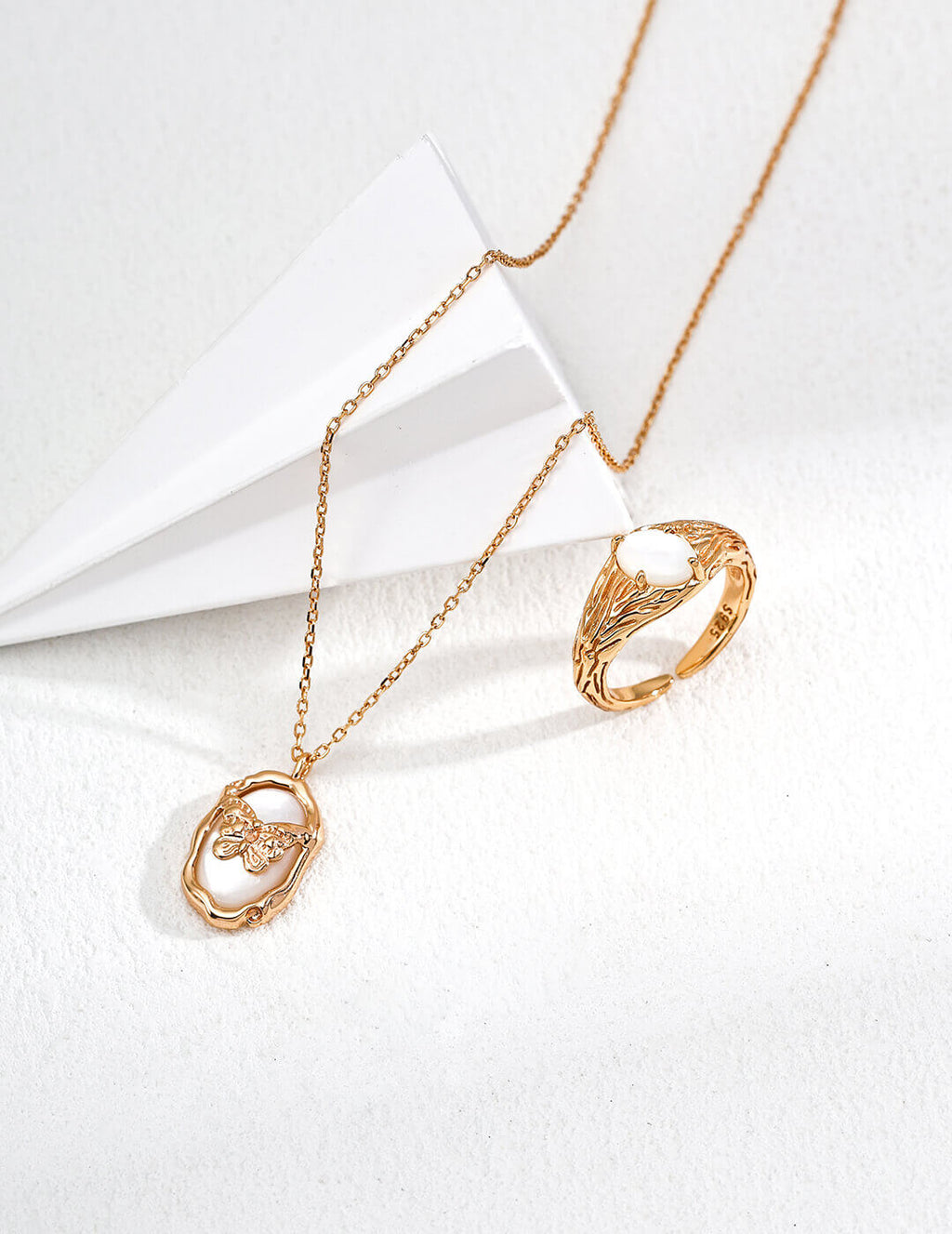 Gold necklace and ring on a white background