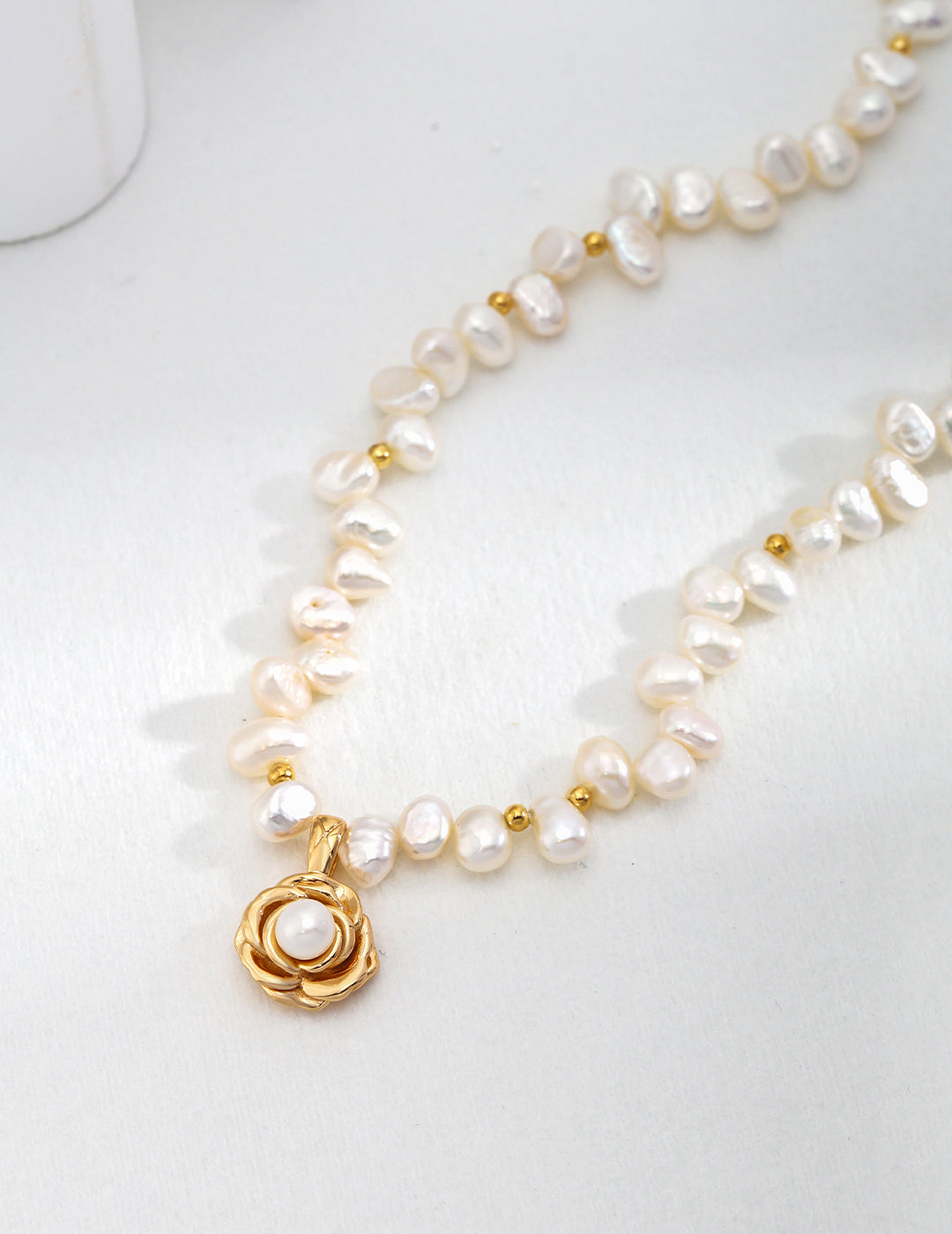Front view of the camellia and natural pearl pendant necklace in vintage gold.
