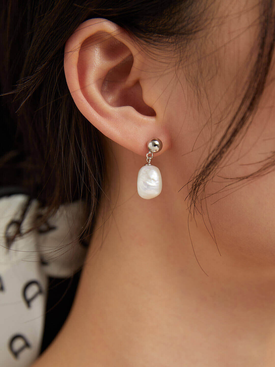 Close-up side view of a model wearing one vintage baroque pearl earring, highlighting its tenderness and elegant drop.