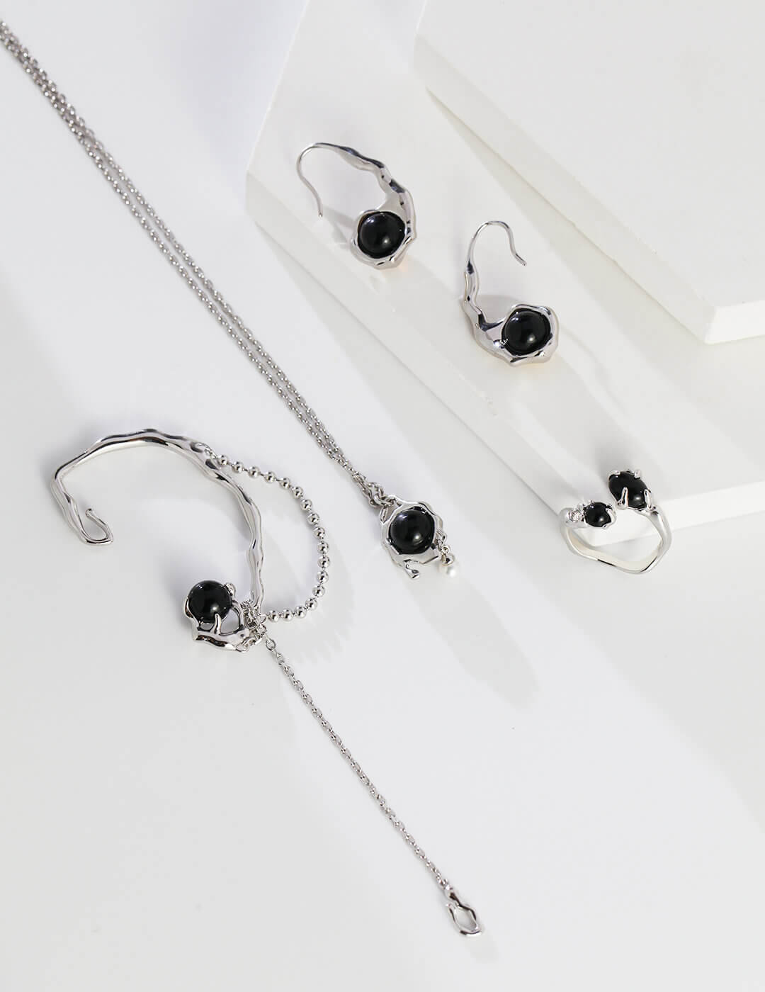Silver jewelry set with black stones on a white background