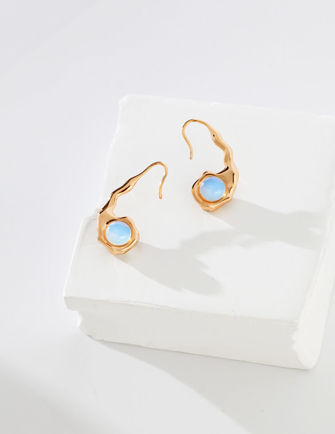 Gold earrings with blue gemstones on a white surface