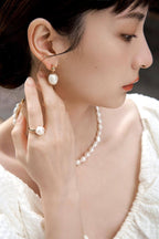 Elegant baroque pearl and silver earrings on a model at a social event, adding a touch of vintage luxury to an evening outfit.