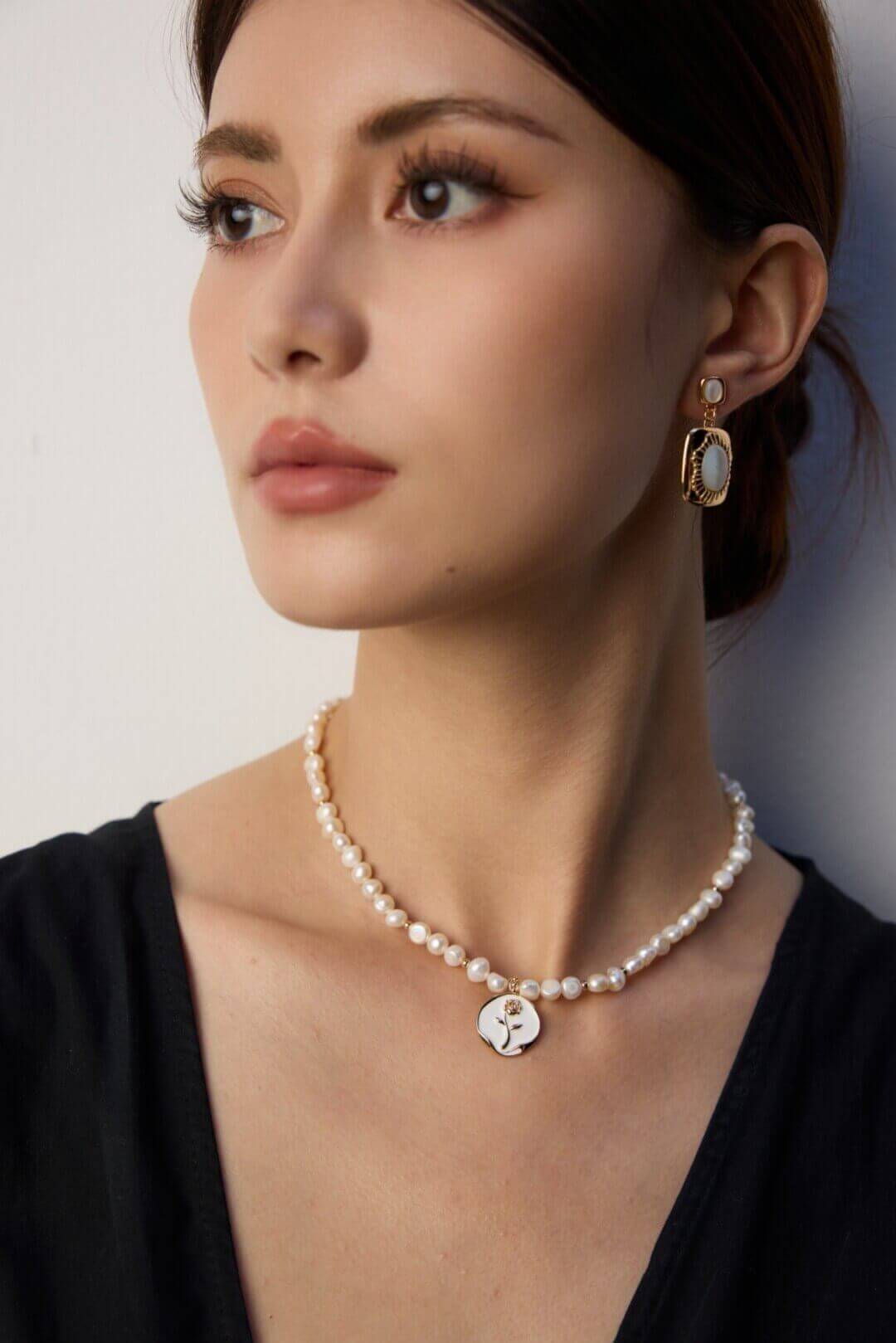 Enamel rose and pearl necklace resting elegantly on model's neck, showcasing its sophisticated style.