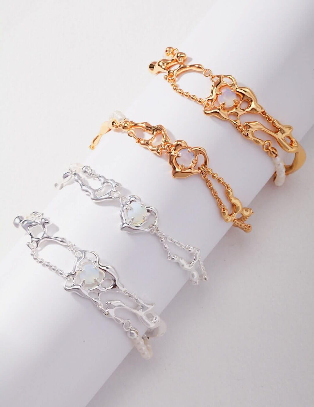 Two gold and silver bracelets on a white surface