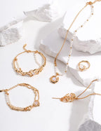 Gold jewelry including bracelets and necklaces on a white stone surface