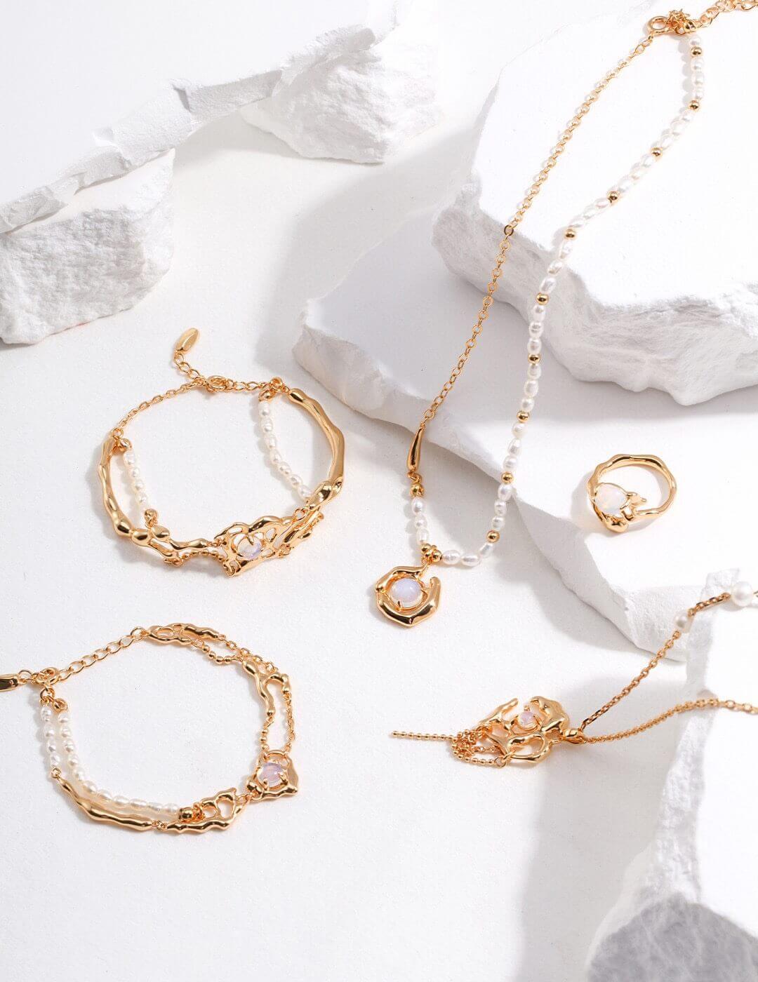 Gold jewelry including bracelets and necklaces on a white stone surface