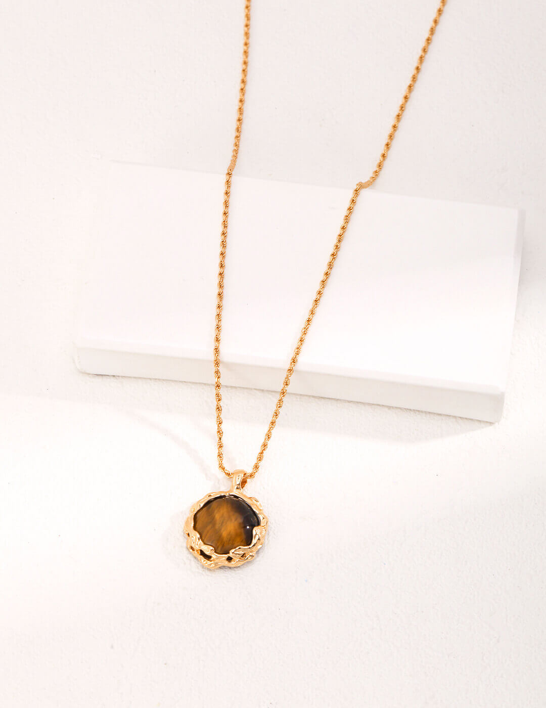 Gold necklace with a round pendant on a white surface