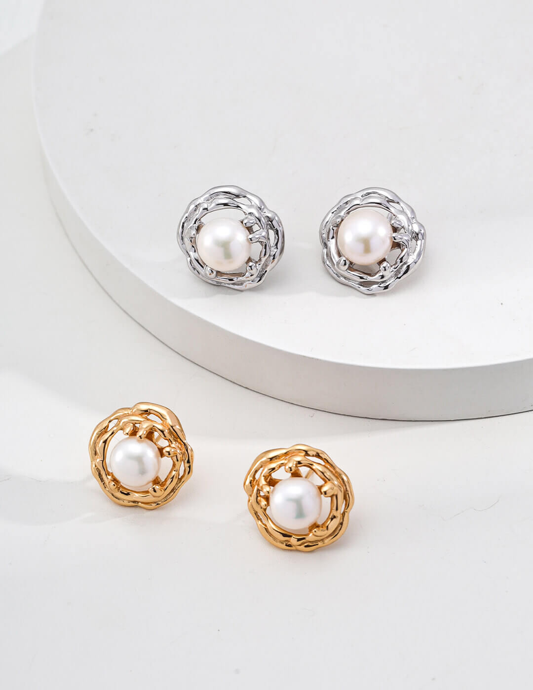 Pair of pearl earrings with gold and silver frames on a white background