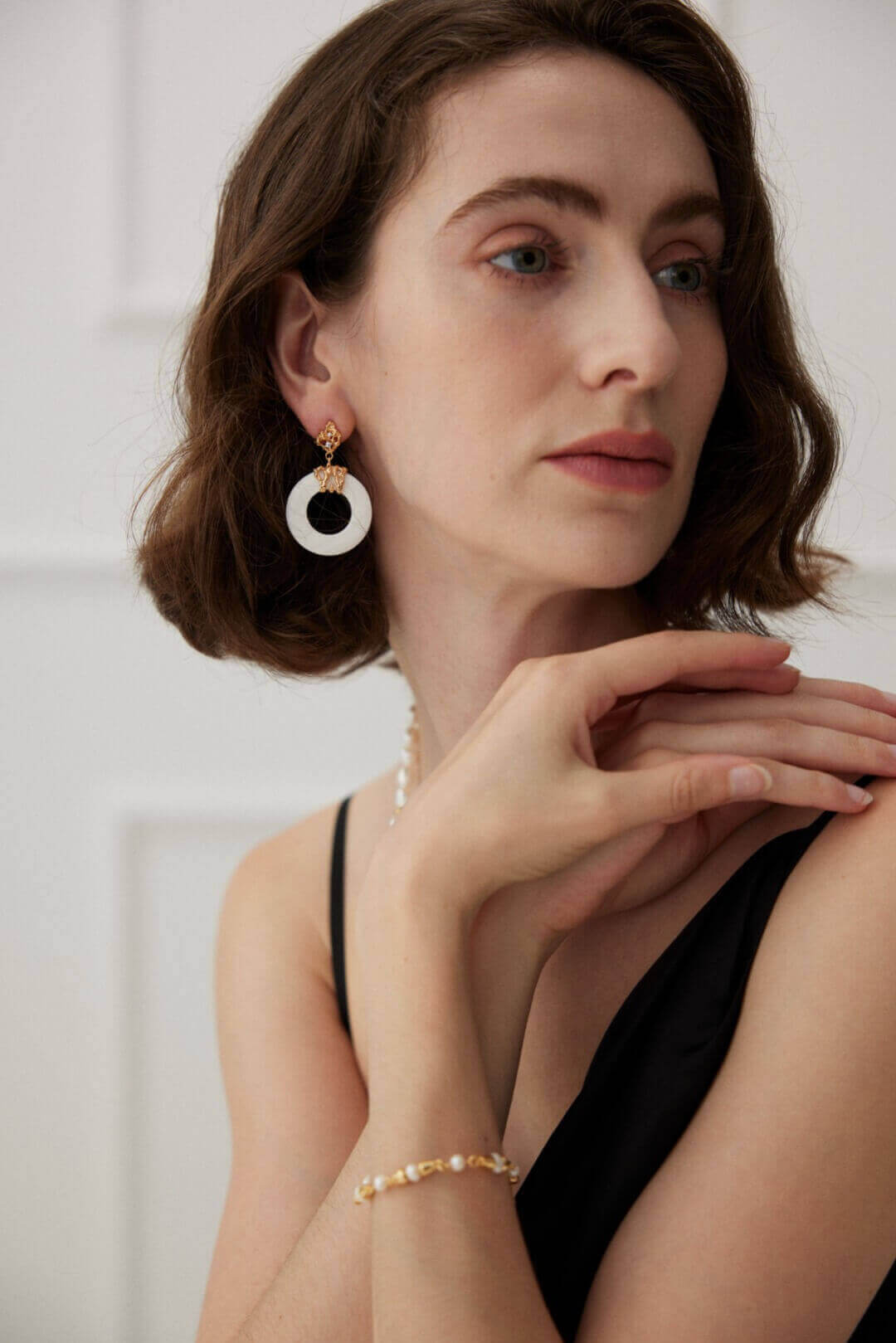 Side view of the hollow-out white shell earrings on a model's ear, showing how the design creates a delicate and airy look against the skin.