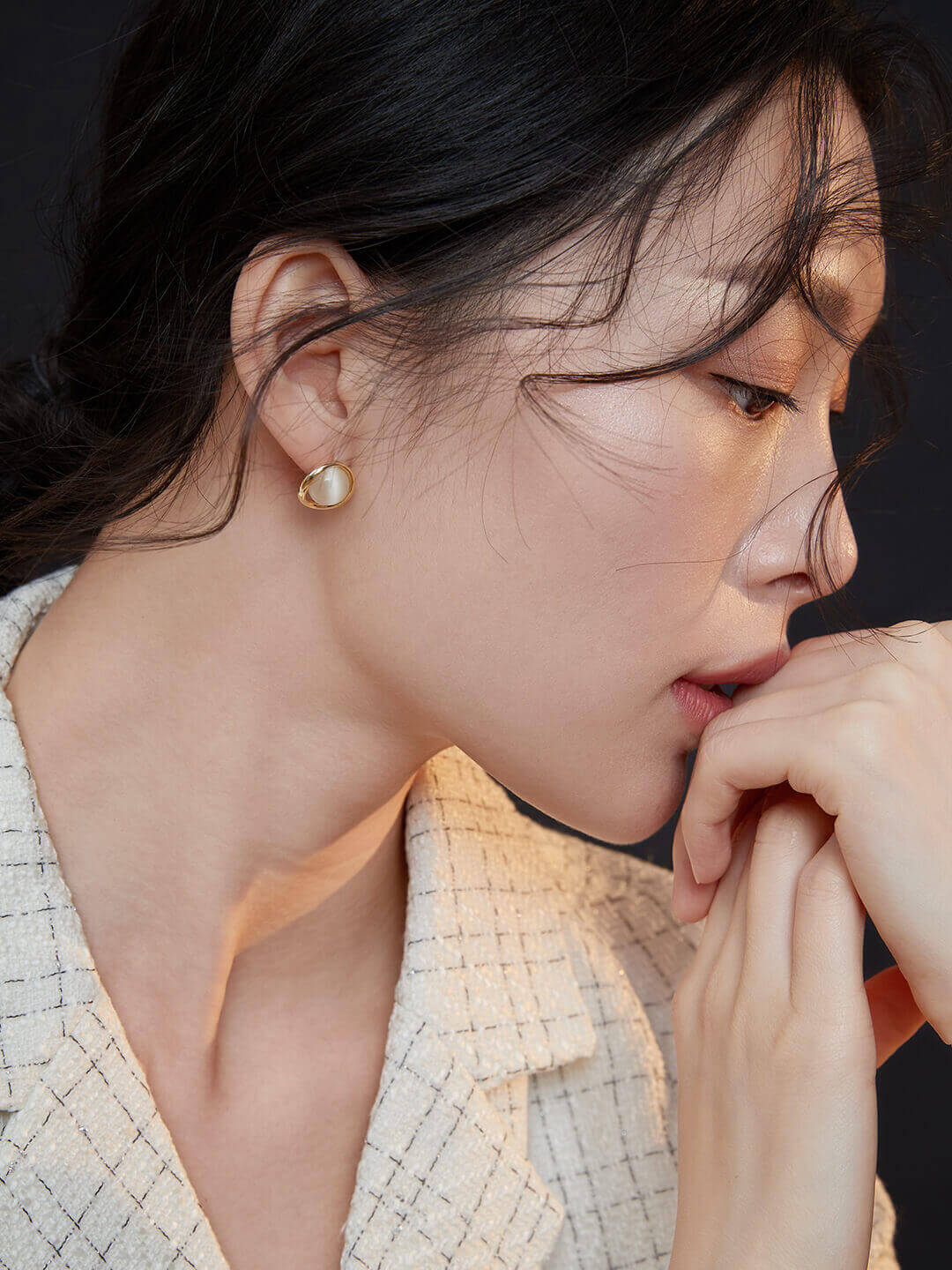 Close-up side view of a woman wearing the K gold cat's eye stud earrings.
