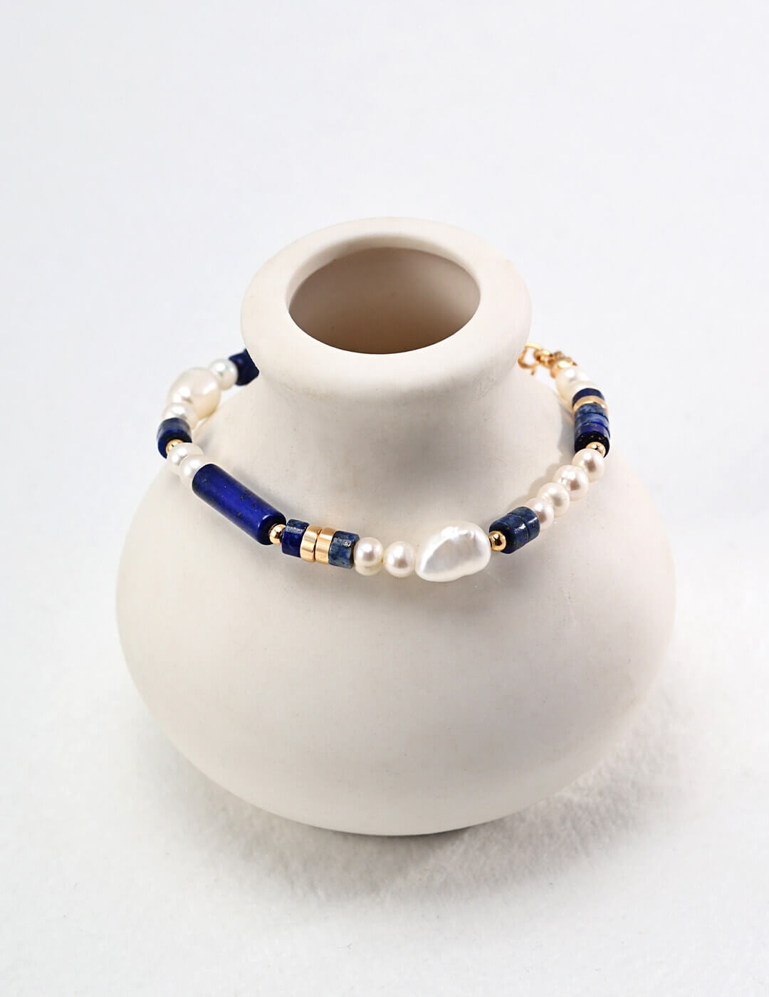Flat lay of the bracelet showing the blue lapis lazuli and irregular baroque pearls.