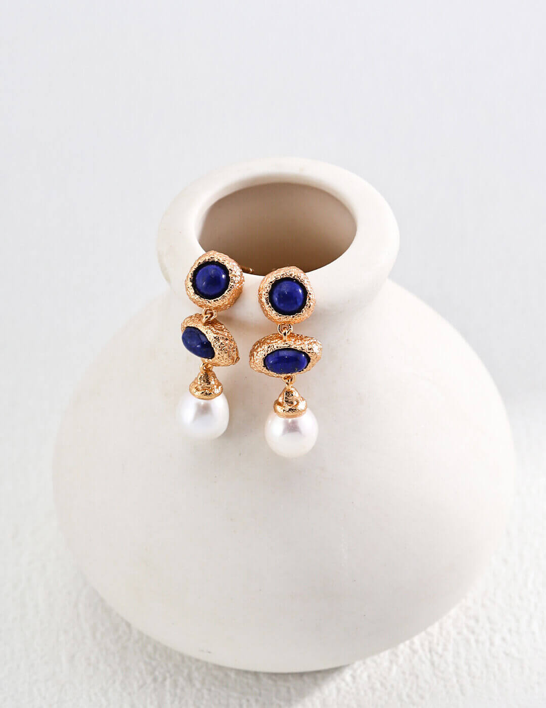 Deep blue lapis lazuli with golden pyrite specks combined with luminous natural pearls in elegant drop earrings.
