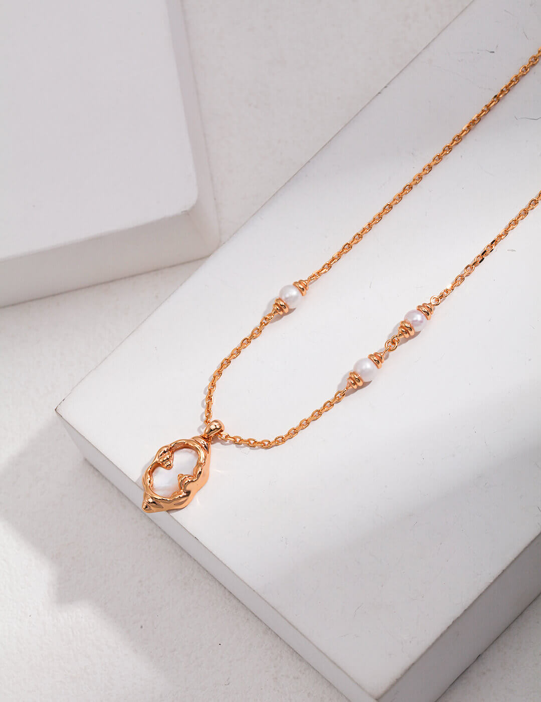 Rose gold necklace with pearl-like beads on a white surface