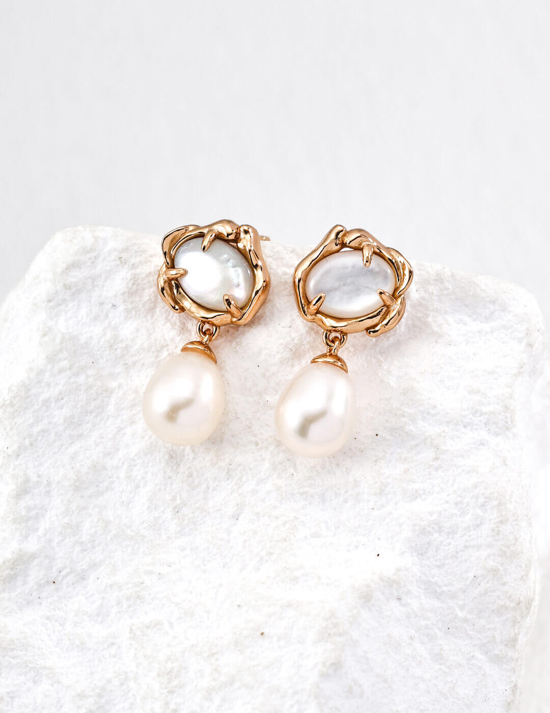 Pair of pearl earrings on a textured white surface