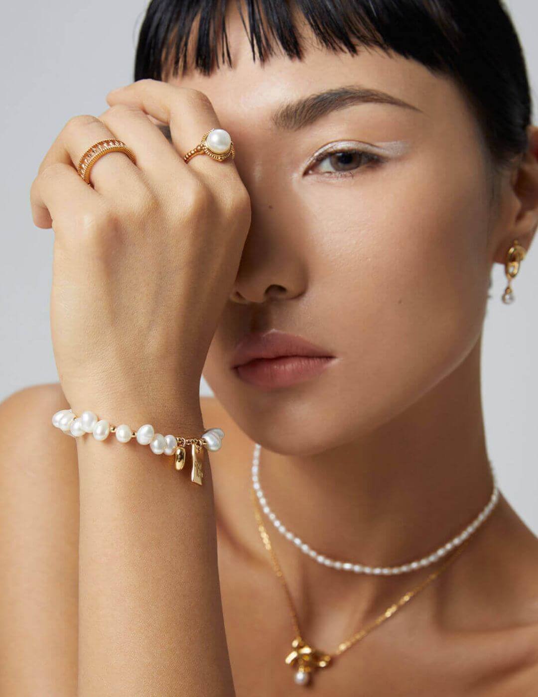 The pearl charm bracelet adding a touch of elegance to a casual outfit.