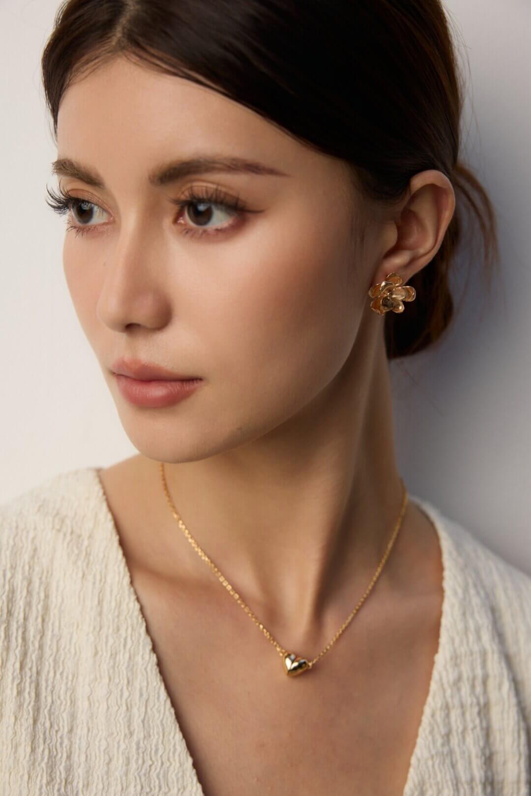 Close-up view of woman wearing the vintage gold floral stud earrings.