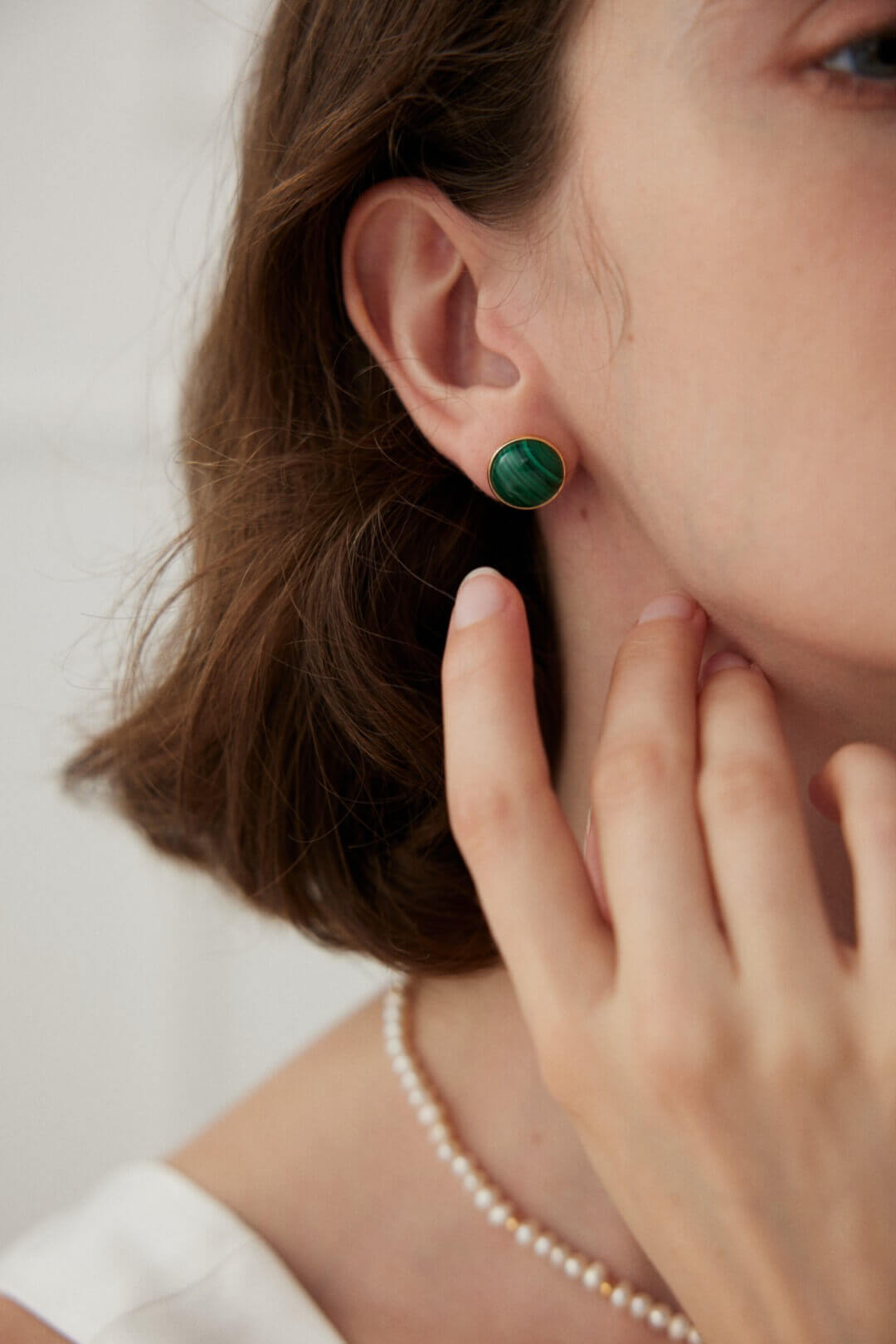 Lifestyle image of a woman wearing the minimalist malachite stud earrings, showing how they look on the ear.