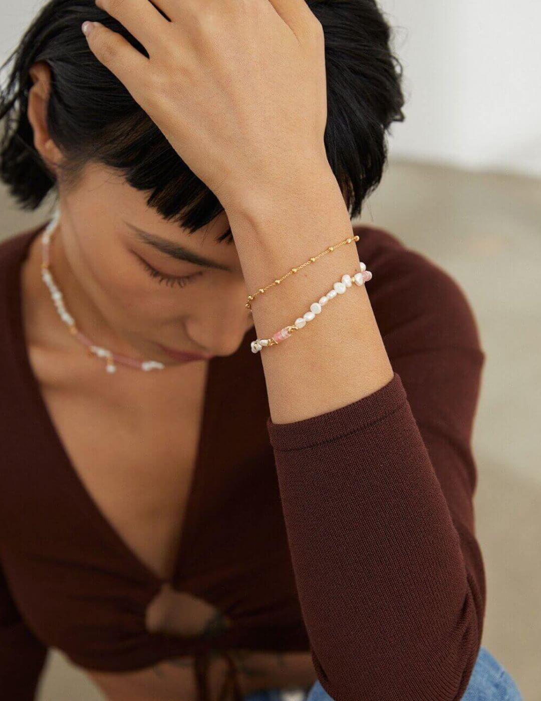 The necklace and bracelet artistically draped over a jewelry stand or mirror.
