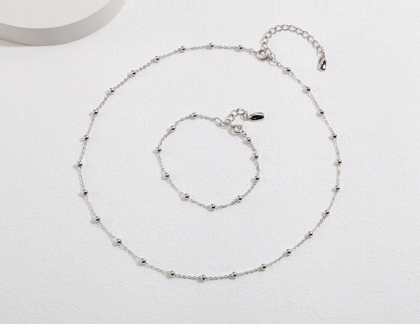 The complete minimalist S925 sterling silver bracelet and necklace set laid out together.