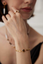 Young woman showcasing bracelet with casual daytime outfit in natural light.
