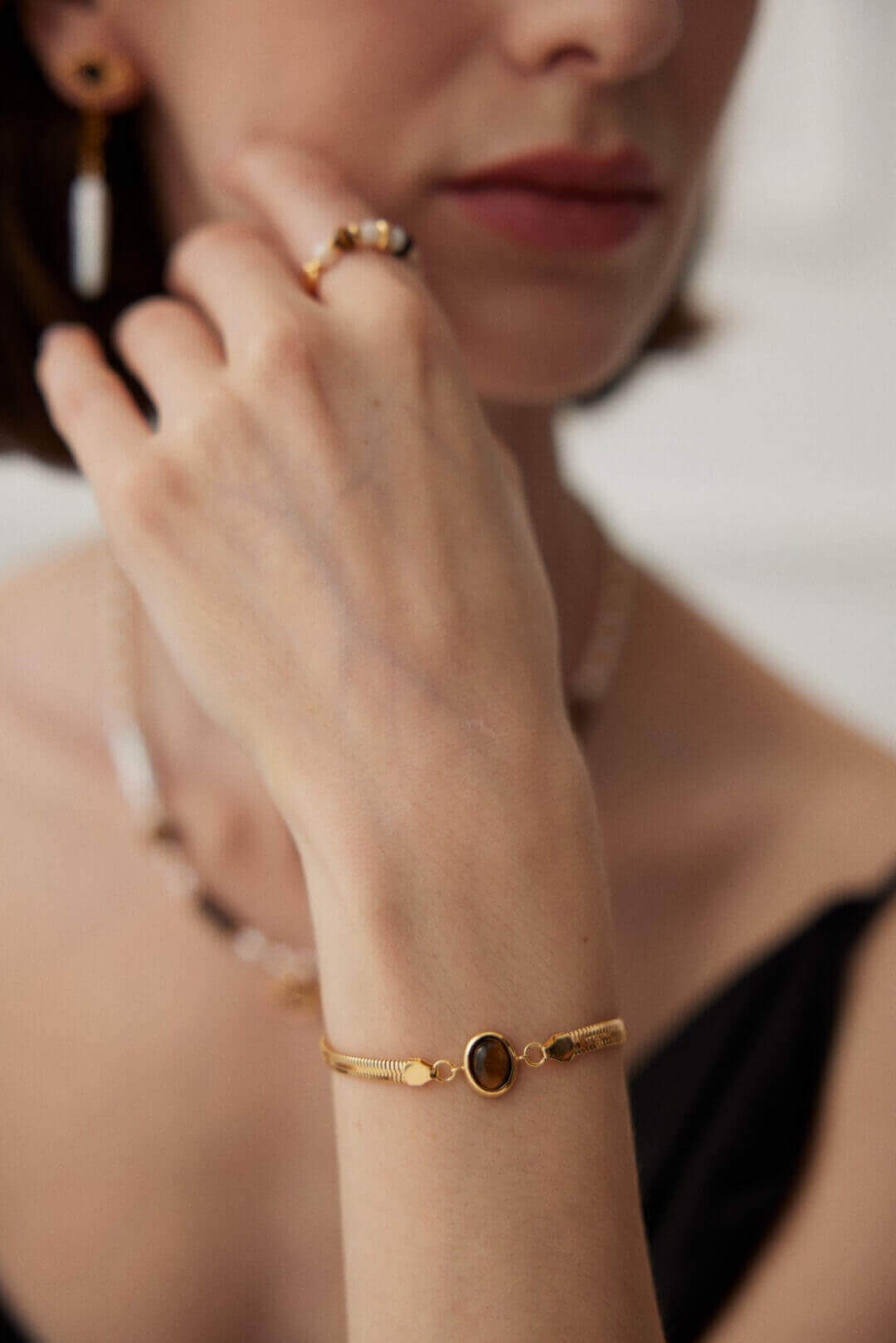 Young woman showcasing bracelet with casual daytime outfit in natural light.