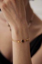 Professional woman wearing bracelet while working on laptop in office setting.