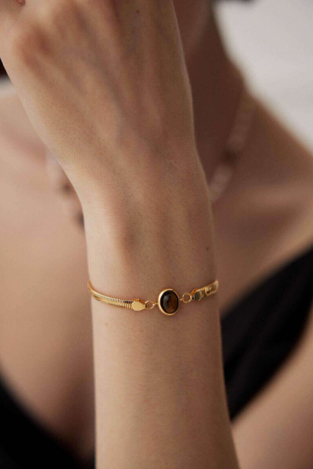 Professional woman wearing bracelet while working on laptop in office setting.