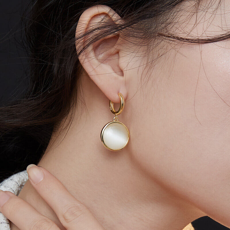 Female model wearing cat's eye stone drop earrings - close-up side view.