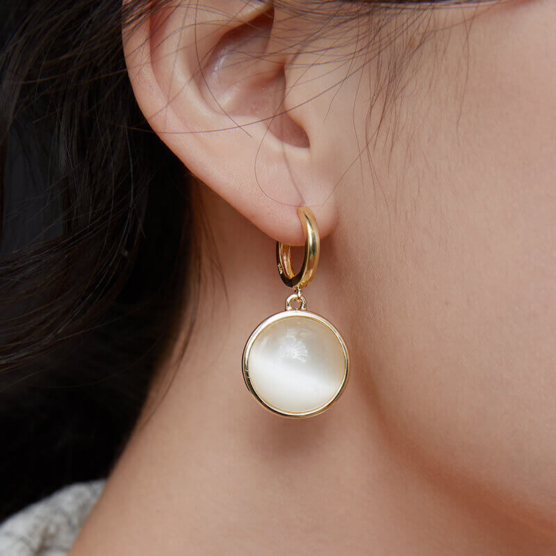 Model showcasing earrings sparkling in bright outdoor sunlight.