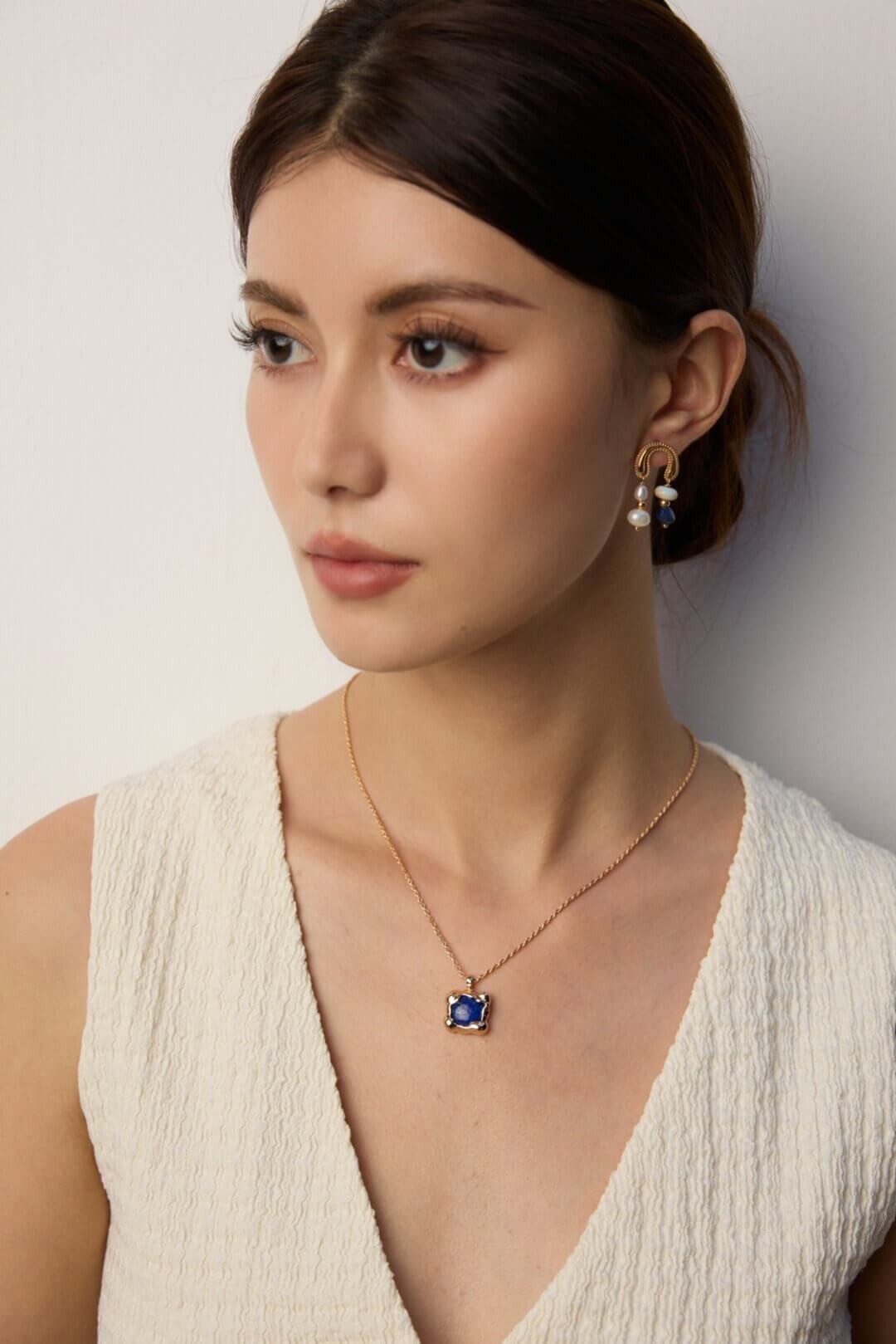 Woman wearing lapis lazuli pendant necklace with casual daytime attire.