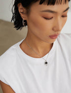 Person wearing a necklace with a pendant, close-up of the neck and head.