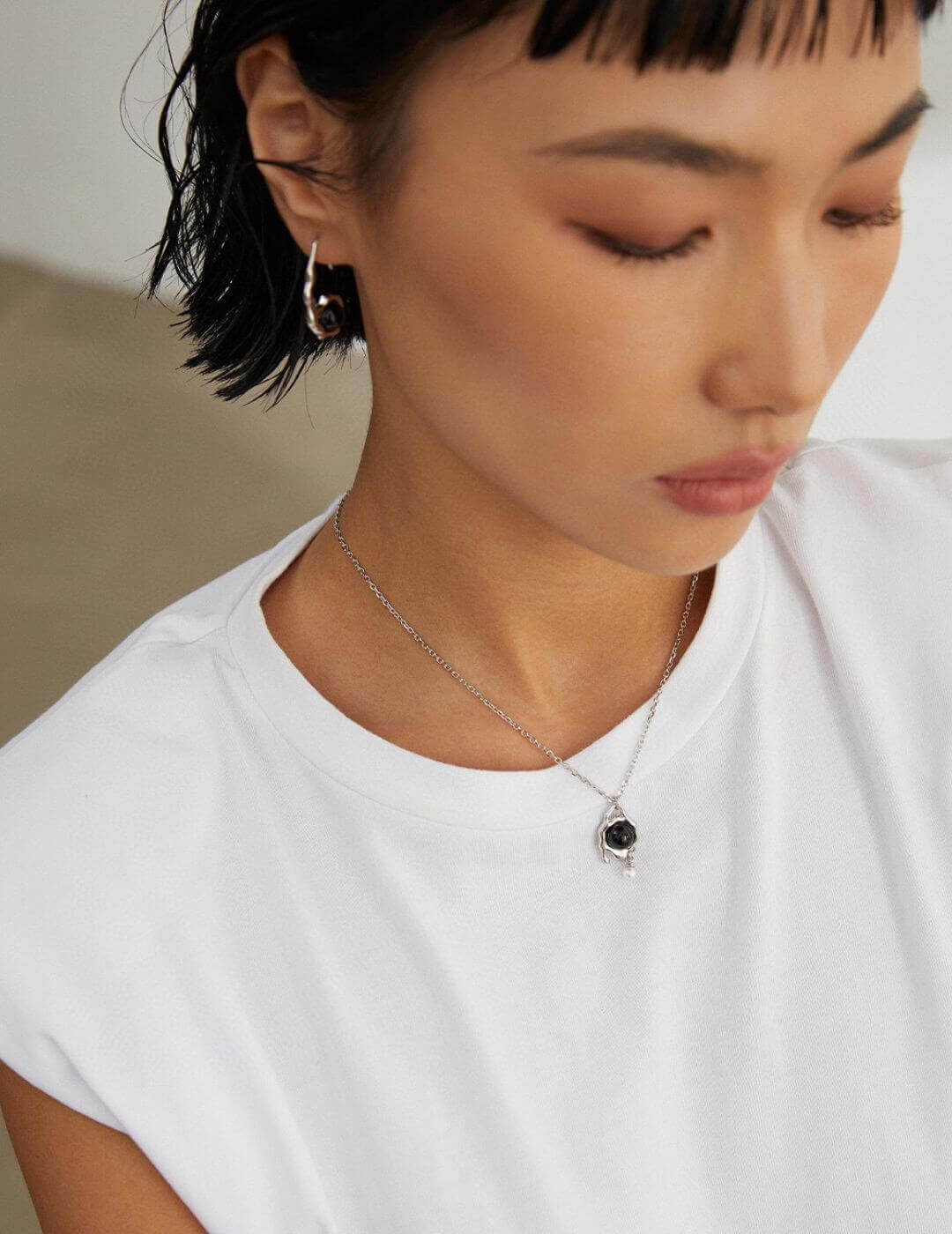 Person wearing a necklace with a pendant, close-up of the neck and head.