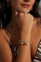 Close-up of a woman's arm wearing two bracelets with a neutral background