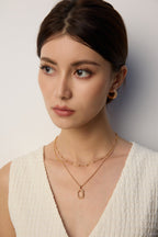 Woman wearing gold jewelry against a neutral background