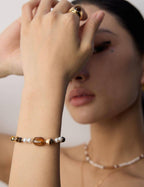 Close-up of a person wearing a bracelet with beads on a plain background