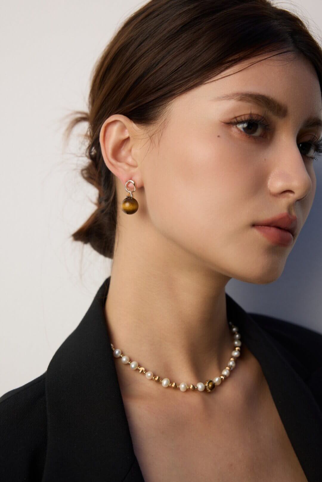 Woman showcasing tiger's eye earrings with casual daytime attire.