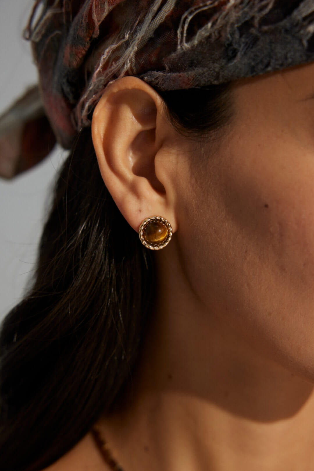 Female model wearing Tiger's Eye stud earrings - close-up side view.