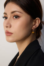 Close-up of a person wearing gold earrings with a neutral background